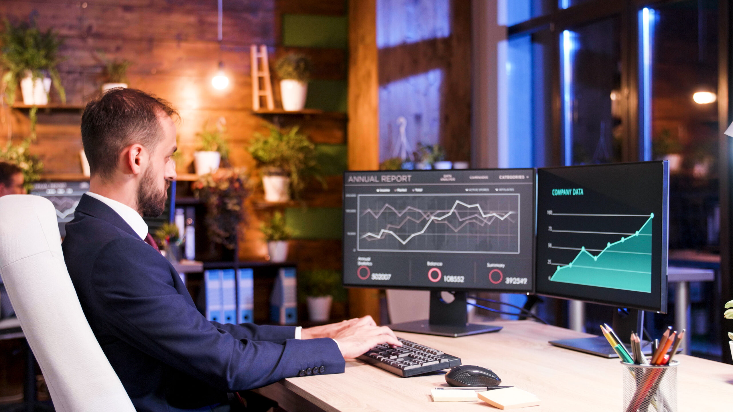Manager working on financial data on two monitors setup
